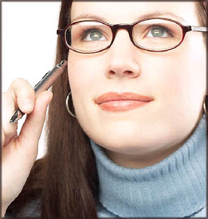 Pensive woman thinking about writing happy birthday messages while holding a pen up to her face.